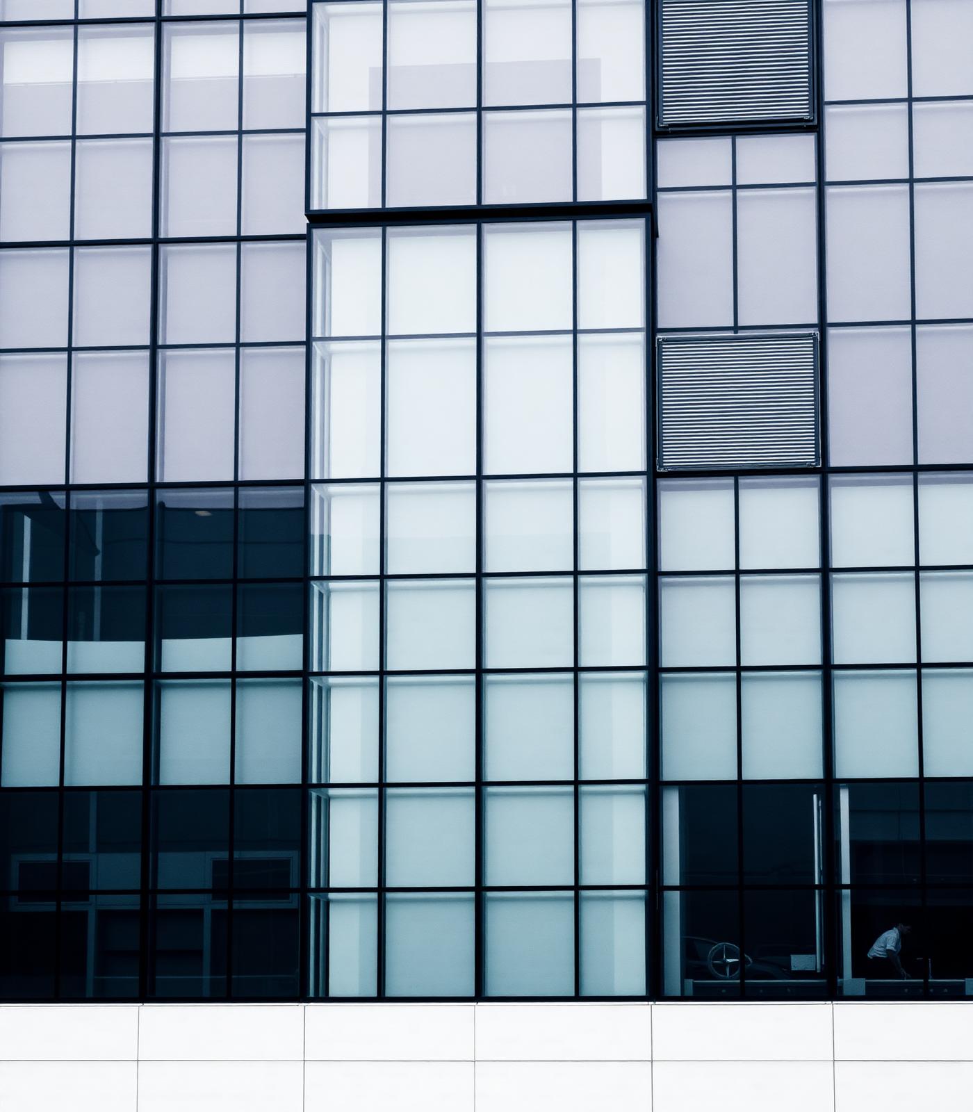 Grid of glass and steel façade on a modern office building, in cool grey tones