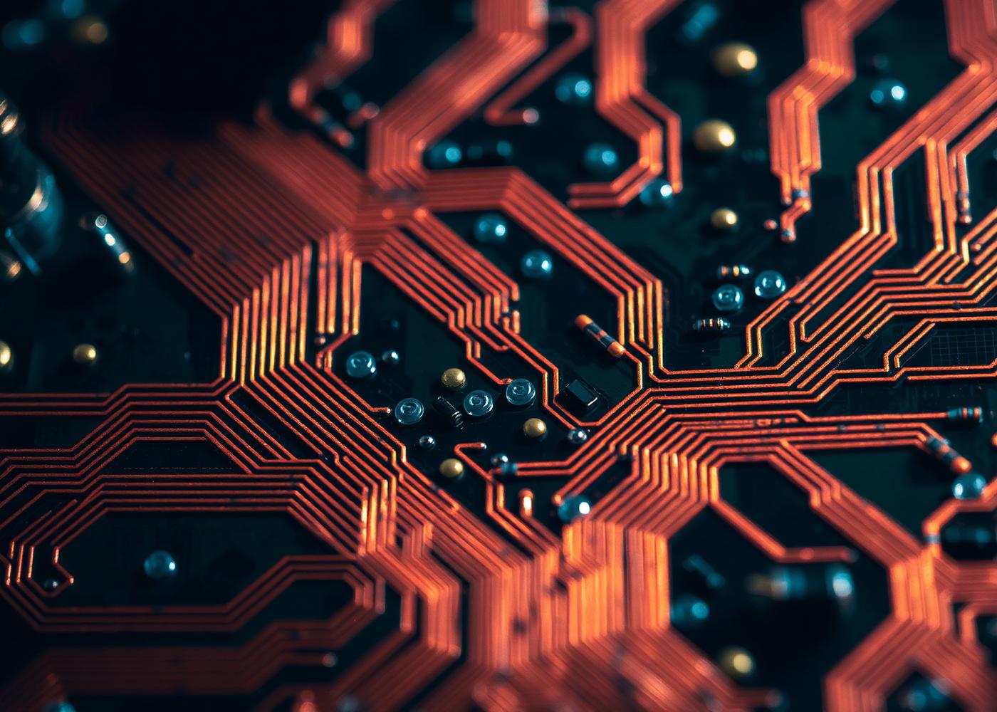 Macro close-up of copper traces on a circuit board illuminated in red